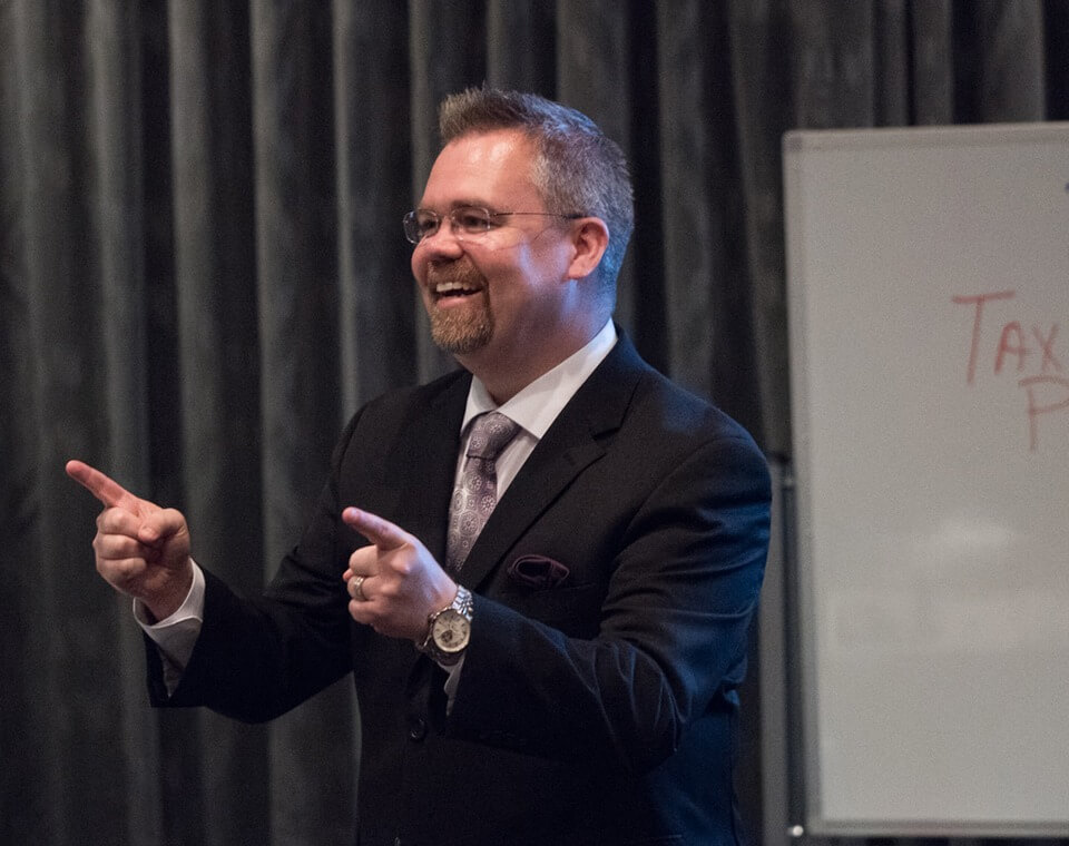 man in suit lecturing and pointing